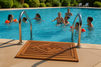 Teak mat positioned at pool steps with families enjoying the water
